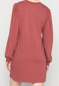 Sukienka z długim rękawem, w stylu oversize, w kolorze przydymionego różu, z marszczonymi akcentami na ramionach, ribbowym dekoltem i elastycznymi mankietami. Gładka tkanina z mieszanki bawełny.