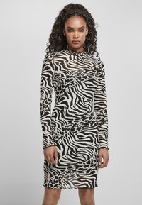Juoda ir balta zebra raštuota ilga rankovė su aukštu kaklu ir scalloped kraštais, pagaminta iš permatomo, lengvo audinio.