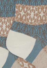 Tessuto a maglia pattern con marrone, crema e azzurro chiaro. Design intricati con motivi floreali e geometrici; texture morbida.