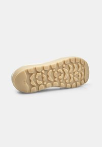 Suola della scarpa con un design testurizzato in un tono beige chiaro, caratterizzata da motivi di battistrada distintivi e una base flessibile e imbottita per una migliore aderenza.