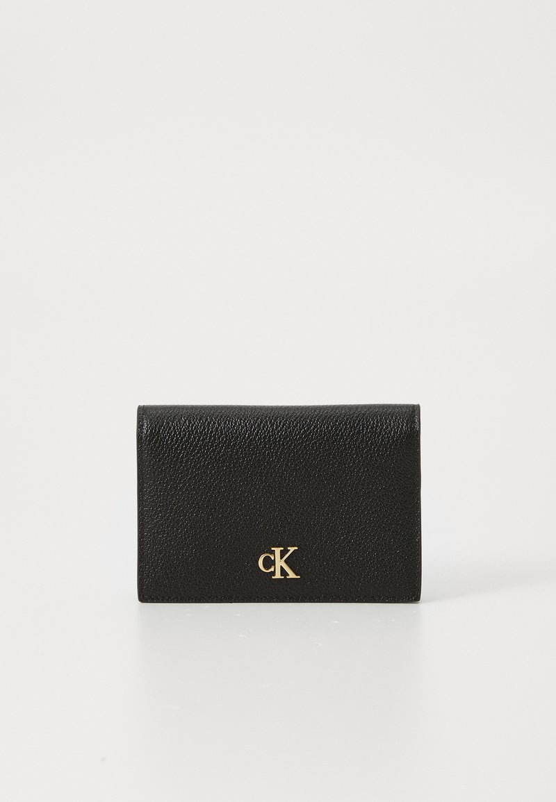 Carteira de pele preta com um acabamento texturizado, apresentando um logo em relevo dourado na frente. Design retangular compacto com fecho de dobra.