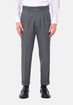 Pantaloni grigi plissettati con vestibilità sartoriale, texture del tessuto, chiusura a bottone e risvolti, abbinati a scarpe eleganti nere.