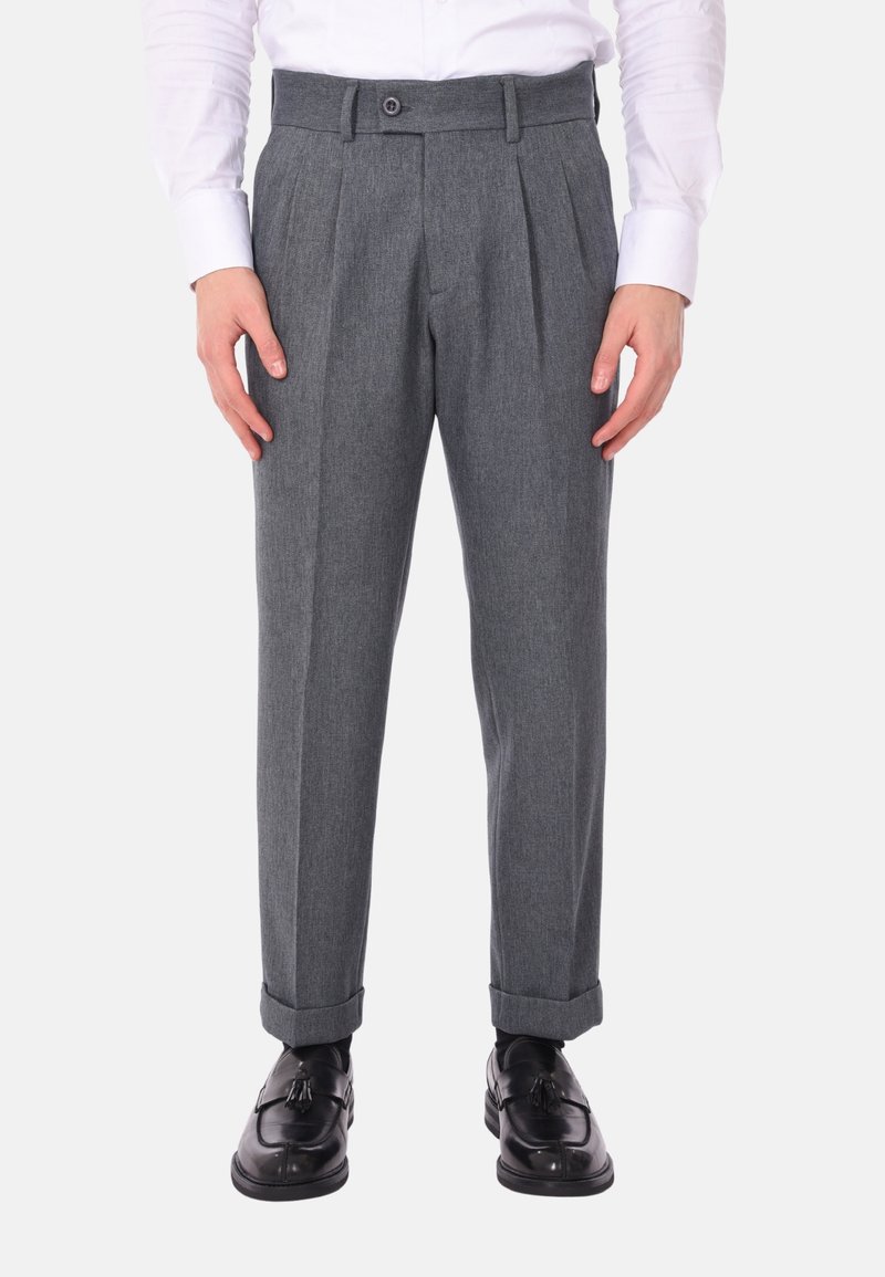 Pantaloni grigi plissettati con vestibilità sartoriale, texture del tessuto, chiusura a bottone e risvolti, abbinati a scarpe eleganti nere.