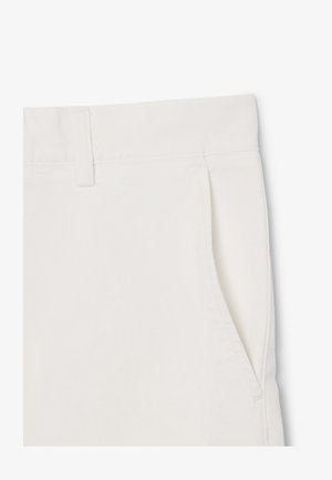 Primer plano de pantalones blancos mostrando la pretina, trabilla y bolsillo lateral con detalles de costura limpia.