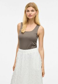 Brązowy top bez rękawów o kwadratowym dekolcie, połączony z białą, fakturowaną spódnicą w kształcie A z elastycznym pasem.