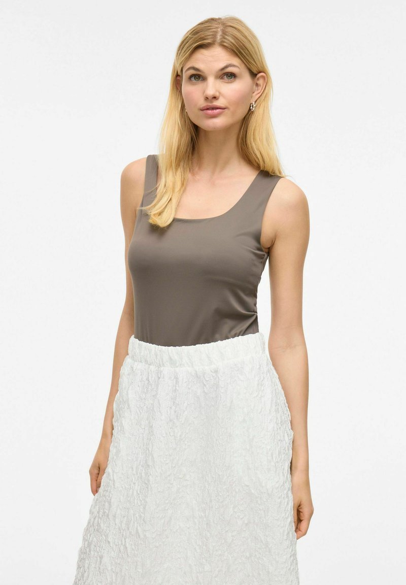 Brązowy top bez rękawów o kwadratowym dekolcie, połączony z białą, fakturowaną spódnicą w kształcie A z elastycznym pasem.