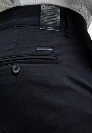 Czarne dżinsy o gładkiej fakturze; posiadają zapięcie na guziki oraz małą metkę "CROSS JEANS" na tylnym kieszeni.