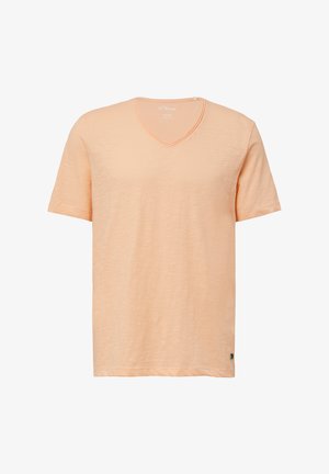 T-shirt à manches courtes, encolure en V, de couleur pêche clair. Tissu doux et texturé avec une légère variation. Étiquette sur l'ourlet latéral.