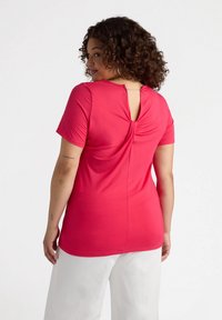 T-shirt aderente a maniche corte in un vivace colore rosa, con un dettaglio di apertura a chiave sul retro e arricciature testurizzate. Tessuto morbido e elasticizzato.