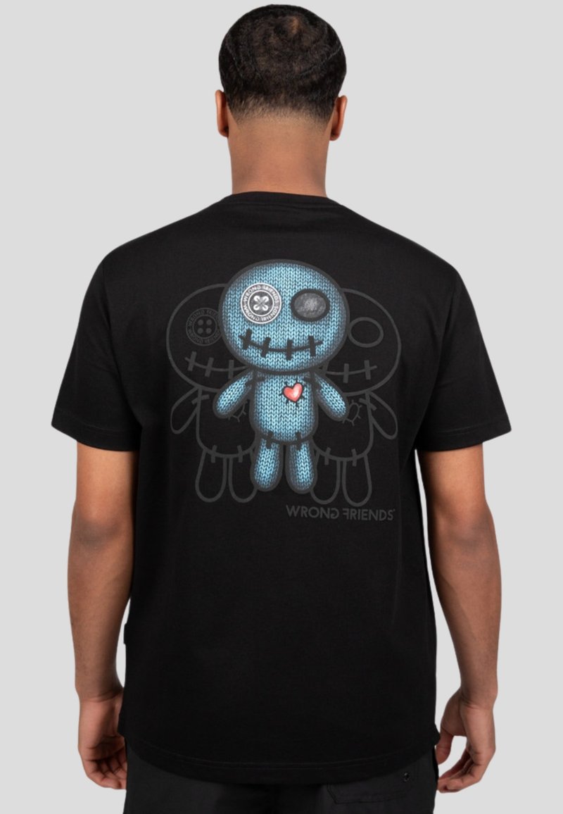 Camiseta negra con un gráfico de un personaje azul de punto, con ojos de botón y un corazón rojo en la parte de atrás, con el texto 'AMIGOS INCORRECTOS' debajo.