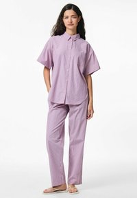 Paars en wit gestreept shirt met korte mouwen en zak, gecombineerd met bijpassende losse broek. Het materiaal lijkt lichtgewicht en ademend te zijn.