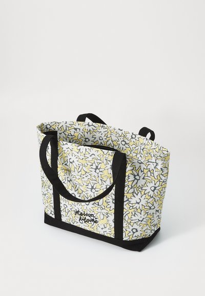 Sac en toile avec motif floral jaune, accents noirs et deux poignées robustes. Comprend un dessus zippé et une base renforcée.
