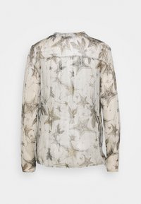 Durchsichtige Bluse mit langen Ärmeln, die ein Sterne- und Blumenmuster in Gold und Grau auf einem hellen Hintergrund zeigt. Sie hat einen runden Ausschnitt und eine Rückenpasse.