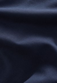 Tissu bleu foncé lisse avec de doux plis et un léger éclat mettant en valeur sa texture.