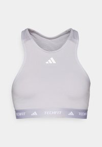 Lysegrå ermeløs sportscrop topp med Adidas-logo på brystet og "Techfit"-merket elastisk bånd nederst.