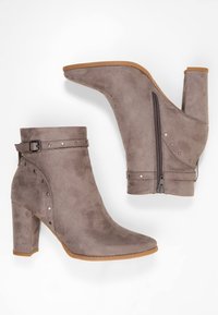 Šedé kotníkové boty z umělé semišové kůže s vysokým širokým podpatkem, nastavitelným páskem s přezkou a dekorativními cvoky, vybavené bočním zipem pro snadné nazouvání.