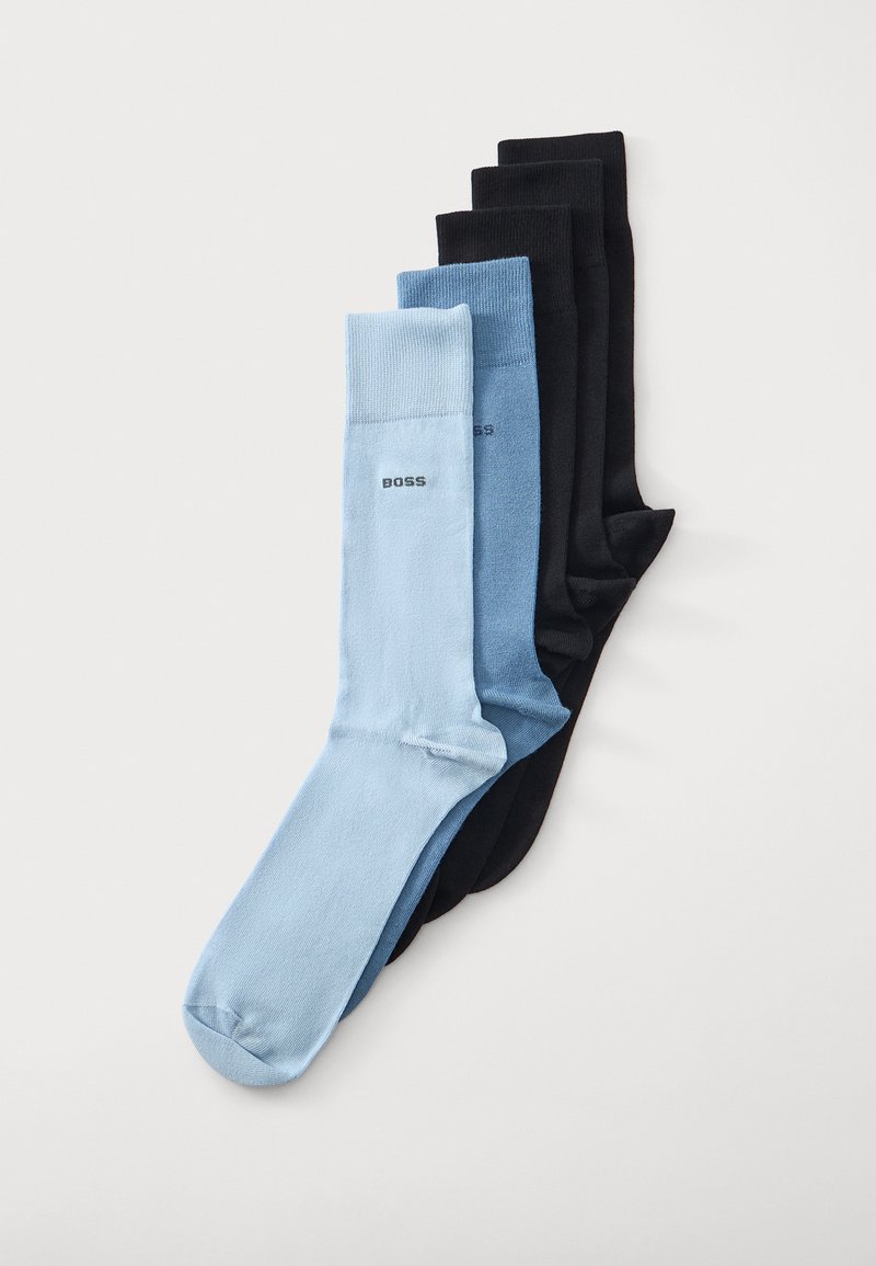 Quatre paires de chaussettes pliées en bleu clair, bleu moyen et deux paires noires, avec le texte « BOSS » sur les chaussettes bleues près du bord-côte.
