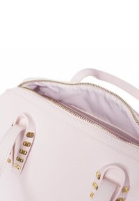 Sac à main texturé rose clair avec fermeture éclair et quincaillerie dorée. L'intérieur est doublé de tissu clair et dispose de poignées courtes avec des accents métalliques.