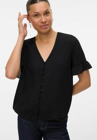 Blusa nera con scollatura a V, maniche corte a volant e bottoni rotondi sul davanti. Realizzata in un tessuto testurizzato, presenta una vestibilità ampia.