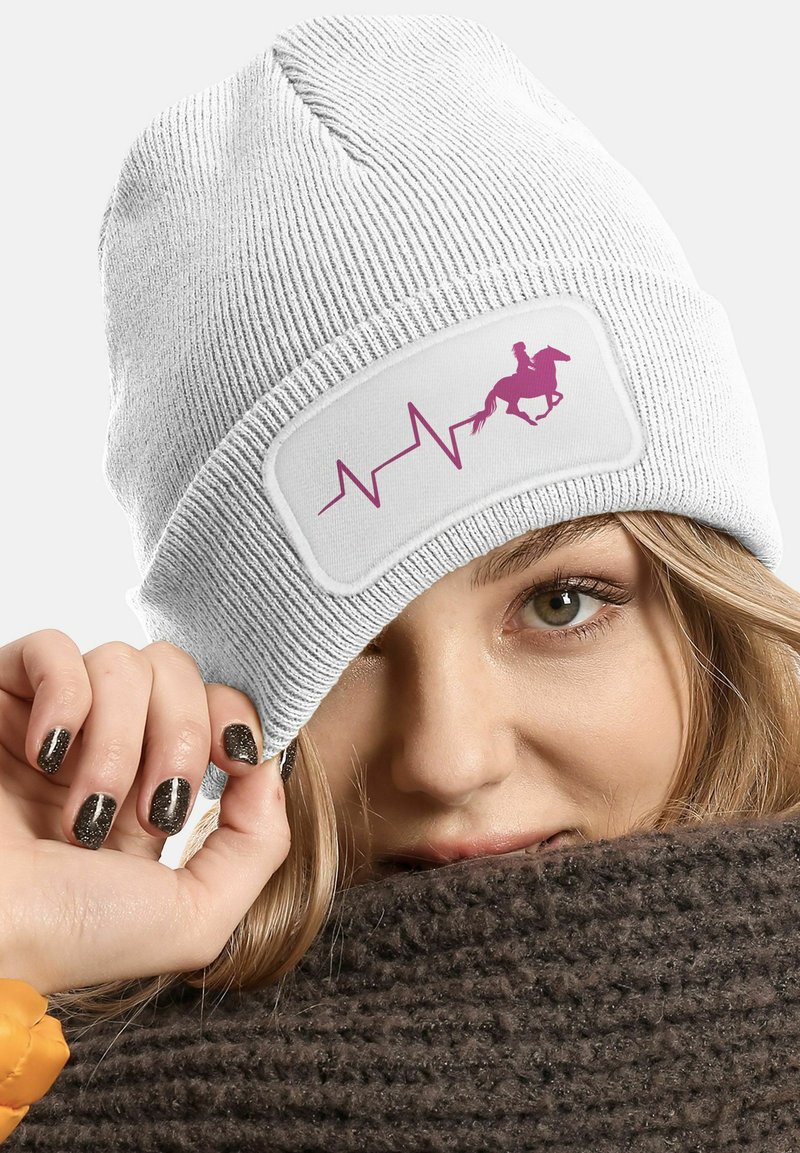 White knitted beanie featuring a pink graphic design of a horse and heartbeat. Soft texture and snug fit, with a wide cuff.