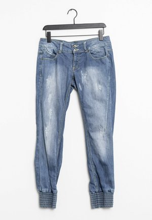 Vaqueros azules de mezclilla con parches desgastados, ajuste cónico, puños elásticos, dos bolsillos delanteros y cierre frontal con botones.