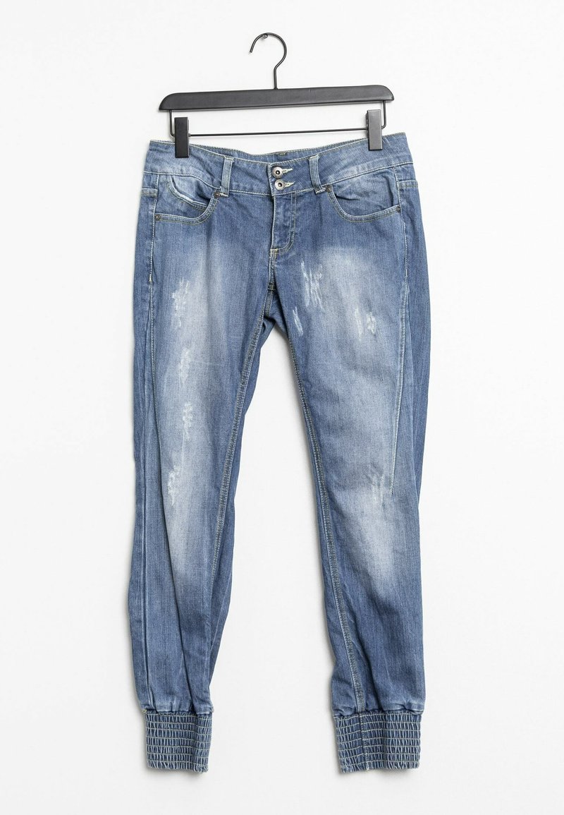 Jean en denim bleu avec des zones usées, coupe fuselée, poignets élastiqués, deux poches avant et fermeture à boutons sur le devant.