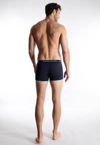 Navy blue cotton boxer briefs with a branded elastic waistband; fitted shape and smooth texture; viewed from the back.