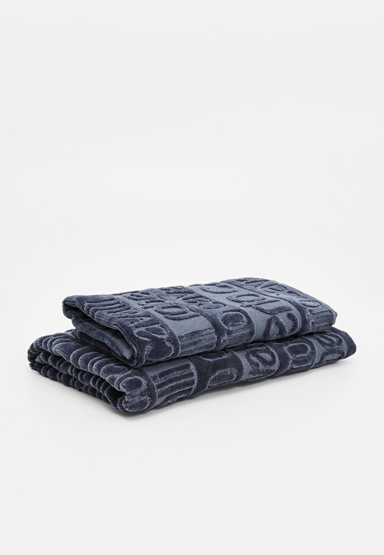 Dunkelblaues, Plüsch-Baumwollhandtuch gestapelt, mit einem strukturierten Design aus geometrischen Mustern und tiefem Prägedruck für zusätzliche Details.