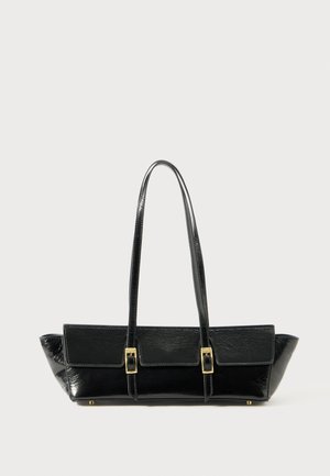 Črna usnjena torbica pravokotne oblike, z dvema dolgima ročajema in zlatimi zaponkami na sprednjem poklopcu. Teksturna površina.