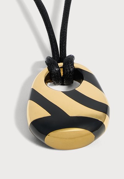 Pendentif rond rayé or et noir sur un cordon noir avec deux boucles passant par un trou en haut.