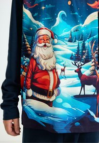 Chemise à manches longues avec un graphique coloré de Santa Claus, un paysage neigeux, des arbres et des rennes sur un fond bleu et blanc.