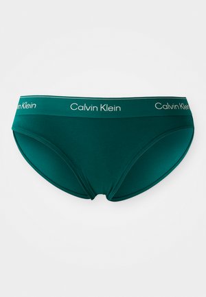 Teal katoenen slip met een brede elastische tailleband waarop het 'Calvin Klein' logo in het wit is afgebeeld. Glad materiaal en een laag uitgesneden ontwerp.