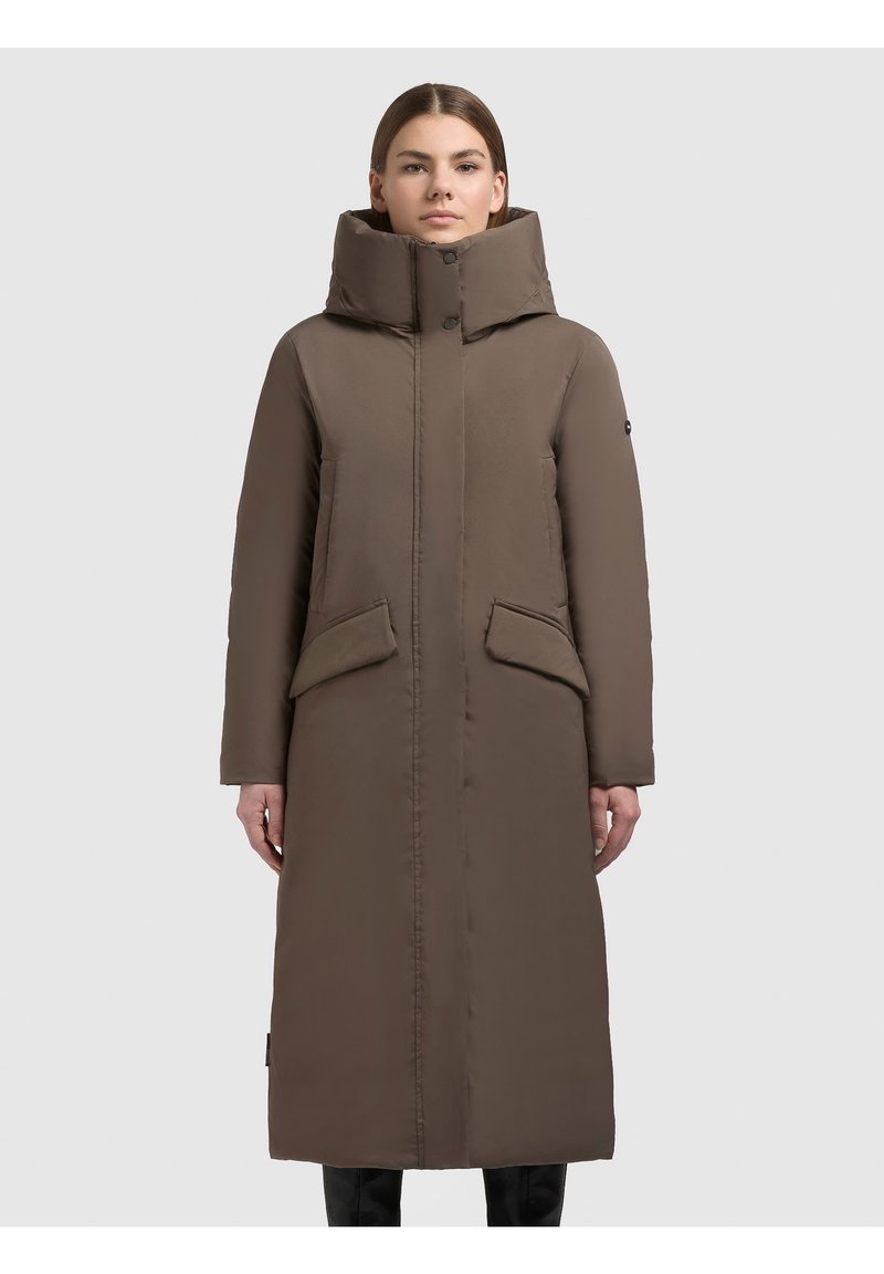 Palton lung, maro, cu umplutură, cu guler înalt, închidere frontală cu capse și două buzunare mari, înclinate. Textură netedă, siluetă dreaptă.