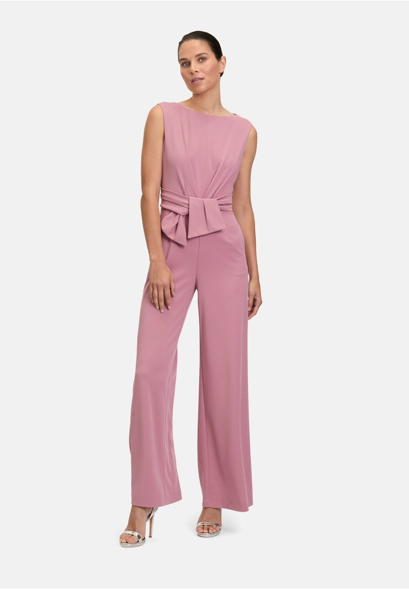 Rosa jumpsuit med vida ben och ärmlös design, med knutdetalj vid midjan, mjukt tyg och minimal silhuett.