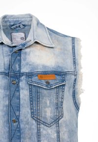 Ljusblå denim väst utan ärmar med fransade kanter, bröstficka med logopatch och silverfärgade tryckknappar. Sliten, urblekt textur.