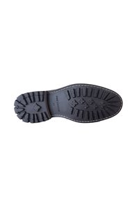 Zwarte rubberen zool met diepe loopprofielen, met een dikke verhoogde structuur en witte stiksel langs de rand. Gemarkeerd met "PRIME LEGEND 41."