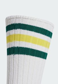 Skarpetki do kolan w kolorze białym z zielonymi i żółtymi poziomymi paskami. Posiadają prążkowaną teksturę i składany mankiet dla dodatkowego komfortu.