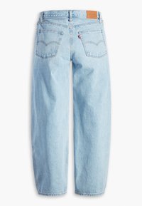 Ljusblå denimjeans med lös passform, med femficksdesign, synlig sömnad och en brun läderlapp på baksidan av midjebandet.