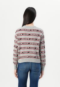 Maglione grigio lavorato a maglia con texture a coste, caratterizzato da un motivo di righe alternate nere e rosse e dalla scritta "JOOP! JEANS" ripetuta.
