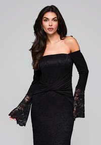 Abito nero off-shoulder con corsetto in pizzo aderente e tessuto fluente. Le maniche lunghe presentano un intricato bordo in pizzo ai polsini. Tessuto liscio in tutto l'abito.