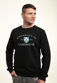 Černá mikina s nápisem "University of Cambridge" a znakem, s žebrovanými manžetami a spodním lemem, vyrobená z měkké, texturované tkaniny.
