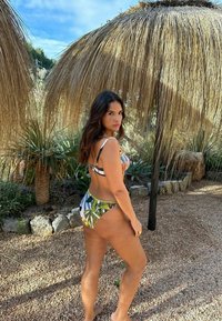 Bikini set s viacfarebným vzorom listov v zelených, modrých a bielych tónoch. Vrchná časť má nastaviteľné popruhy a spodný diel s nízkym pásom a zberným detailom.