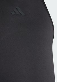 Μαύρο αθλητικό τοπ από λείο, ελαστικό ύφασμα. Διαθέτει διακριτικό μαύρο λογότυπο και επίπεδες ραφές, σχεδιασμένο για άνεση και κινητικότητα.