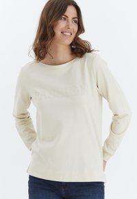 Sudadera de manga larga en color crema con la palabra "PASIÓN" en relieve en el pecho, con un corte relajado y una textura de algodón suave.