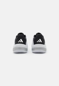 Adidași negri și albi cu un superior din țesătură texturată, guler căptușit și o talpă albă cu un model în zigzag.