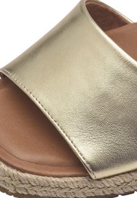 Gold metallic slide sandal with a wide strap, soft brown insole, and jute-wrapped sole. Smooth texture with subtle sheen.