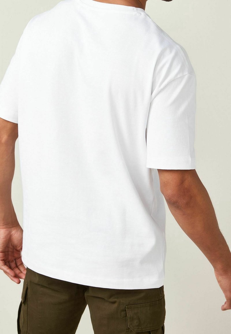 Hvid bomulds t-shirt med korte ærmer, rund hals og en afslappet pasform. Glat tekstur, ingen synlige mønstre eller accenter. Bagudvendt visning.