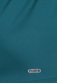 Tela verde azulado con una superficie texturizada, que presenta pequeños puntos elevados. Un logo "ProW" en gris se encuentra situado hacia la parte inferior.