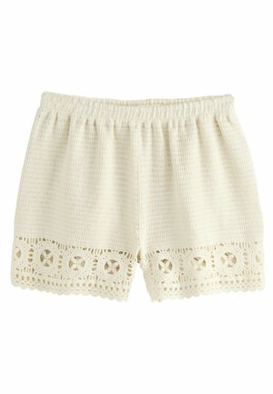 White knit shorts with an elastic waistband and lace trim at the hem, featuring circular cut-out patterns along the edges.