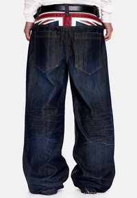Σκούρο μπλε τζιν παντελόνι με φαρδιά γραμμή, διαθέτει πίσω τσέπες και ζώνη μέσης με το λογότυπο που εμφανίζει το σχέδιο της σημαίας Union Jack.